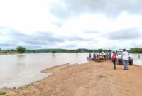 Flooded area in Koukou, Chad. MSF staff, a car, and people are standing on land by the waterlogged area. 