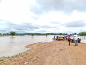 Flooded area in Koukou, Chad. MSF staff, a car, and people are standing on land by the waterlogged area. 