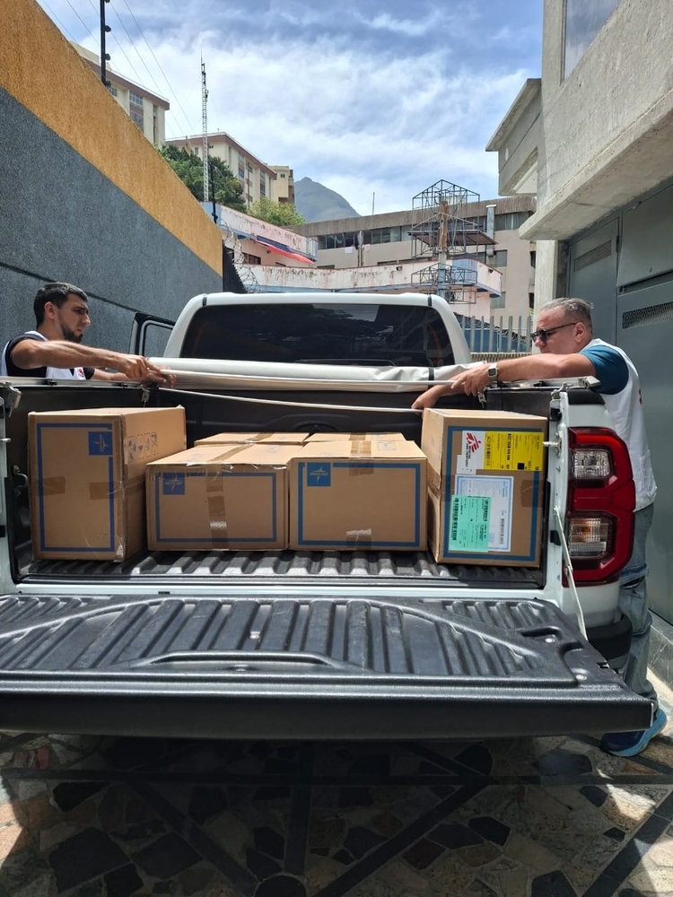 Deux membres du personnel de MSF chargent des caisses de fournitures médicales dans un pick-up dans une allée entre deux bâtiments, dans le cadre de l’intervention d’urgence à la suite du double séisme qui a frappé le Venezuela le 24 juin 2026.
