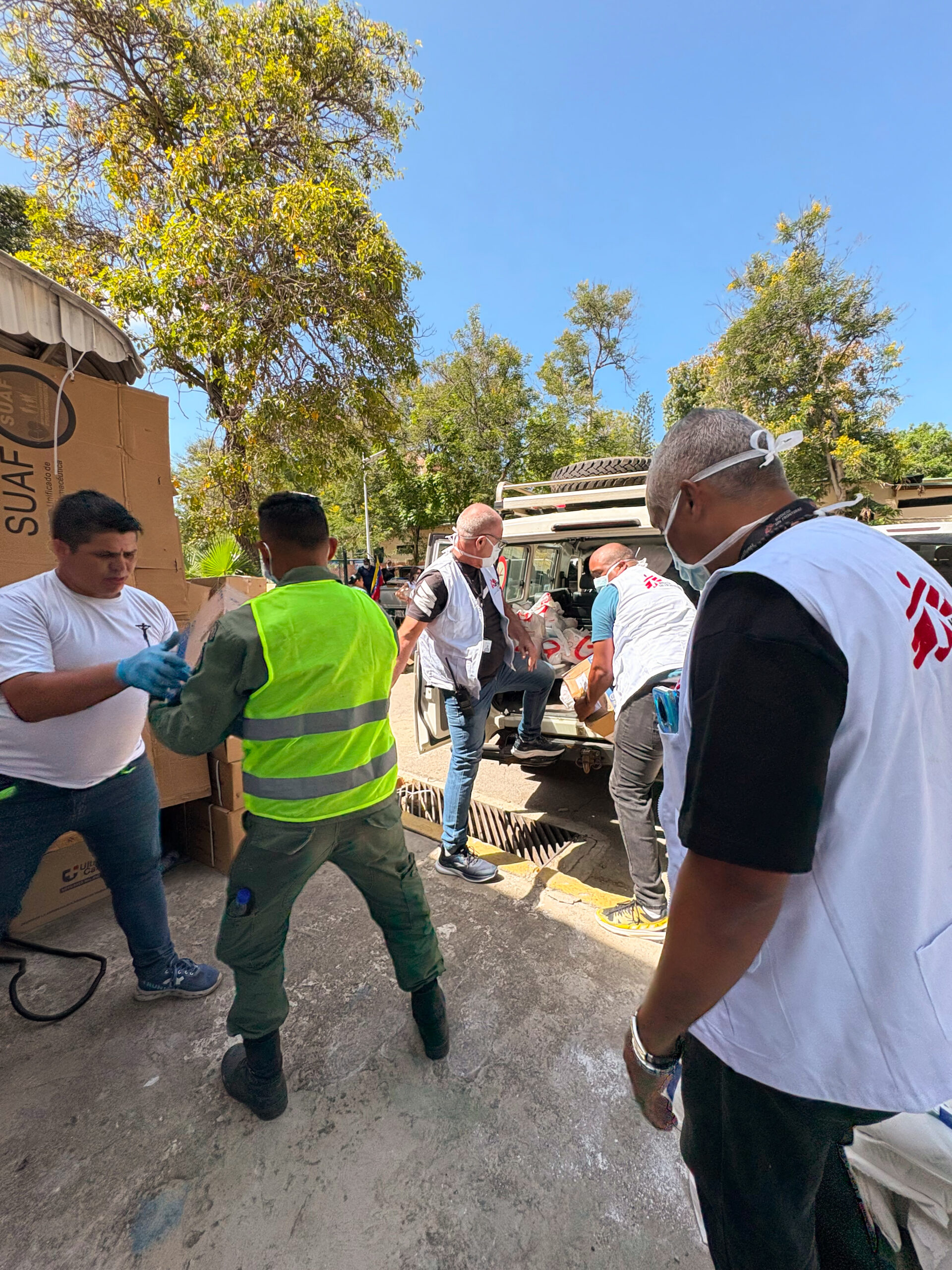 Des membres du personnel de MSF, vêtus de vestes arborant le logo de MSF, déchargent des caisses de fournitures médicales d’un véhicule après le double séisme du 24 juin.