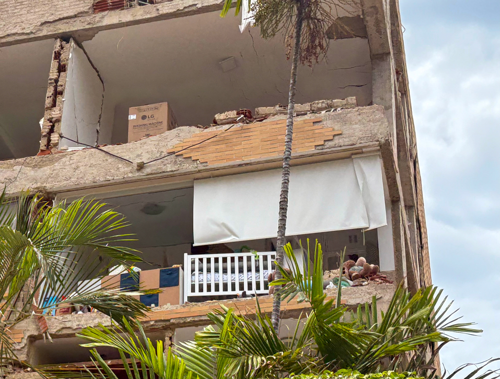 Vue d’un immeuble endommagé lors des séismes du 24 juin au Venezuela. Un mur effondré laisse entrevoir une pièce où se trouve un lit de bébé. Venezuela, 2026.
