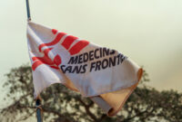 Gros plan sur un drapeau flottant, sur lequel on distingue partiellement le logo de Médecins Sans Frontières.